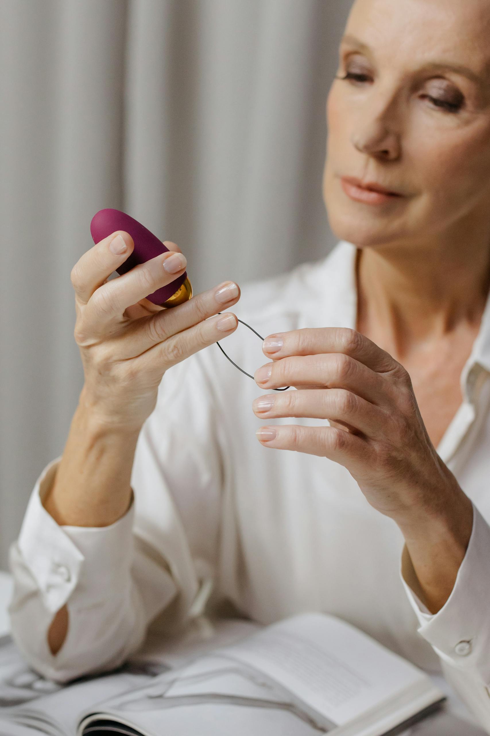 une femme senior en train de regarder un jouet intime attentivement